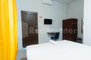 a bedroom with a white bed and a wooden door at Teratai Guesthouse at RS Adam Malik Medan Mitra RedDoorz in Medan