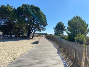 a wooden path to the beach with a fence and trees at En Dro, Rez-de-jardin à Carnac in Carnac