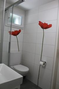 a bathroom with a toilet and red flowers on the wall at NEB-THUN Studio am Thunersee in Thun