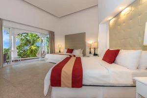 - une grande chambre avec 2 lits et une grande fenêtre dans l'établissement Shana by the Beach Manuel Antonio, à Manuel Antonio