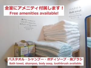 a sign with a stack of towels on a shelf at Tateyama Wheels Guest House in Tateyama