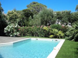 una piscina en un patio con árboles y flores en Villa Esterel Plage, en Saint-Raphaël
