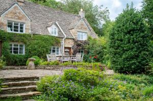 a stone house with a table and chairs in a garden at Top Cottage, Oddington in Adlestrop