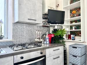 cocina con fogones y TV en un estante en Il Sole e la Luna - Apartment, en Montesilvano
