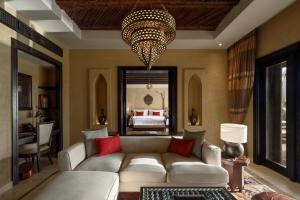 a living room with a couch and a chandelier at Anantara Qasr al Sarab Desert Resort in Jurayrah
