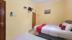 1 dormitorio con 1 cama y TV en la pared en RedDoorz Syariah At Endrayanti Inn RSUD Yogyakarta, en Timuran