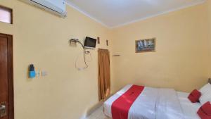 1 dormitorio con 1 cama y TV en la pared en RedDoorz Syariah At Endrayanti Inn RSUD Yogyakarta, en Timuran