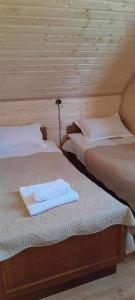 two beds in a wooden room with towels on them at Cottage Mzispira/Cottage sunny side in Sioni