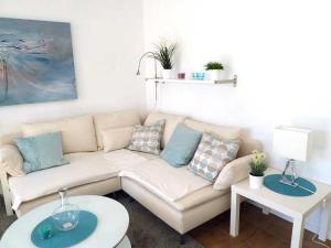 uma sala de estar com um sofá branco e duas mesas em Haus Gloria em Sierksdorf