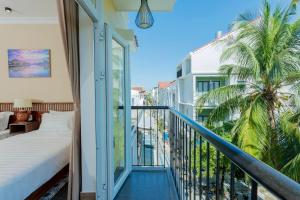 a bedroom with a balcony with a bed and palm trees at Kemi House Hoi An in Hoi An