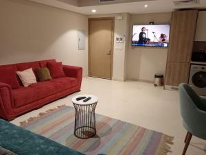 Mangroovy apartament El gouna في الغردقة: غرفة معيشة مع أريكة حمراء وتلفزيون