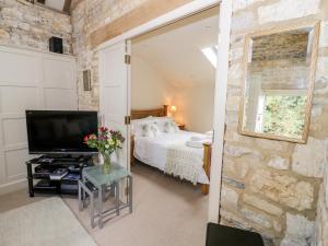 um quarto com uma cama e uma televisão num quarto em Old Bothy em Shipston on Stour