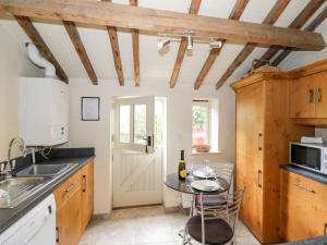 uma cozinha com armários de madeira e uma mesa em Old Bothy em Shipston on Stour