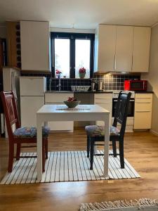 een keuken met een witte tafel en 2 stoelen bij Lugnt,centralt, parkering,altan. in Växjö