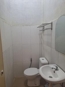a white bathroom with a toilet and a sink at RON'S Guest House Berastagi in Berastagi +36 photos