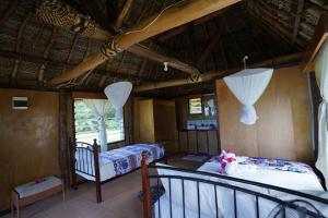 Waya Lailai Eco Haven في Wayasewa Island: غرفة نوم بسريرين وبلكونة في غرفة