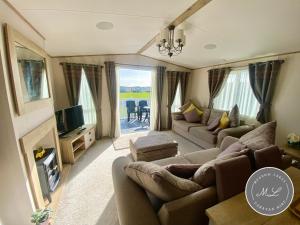a living room with a couch and a tv and a fireplace at Waterside mini lodge - pet friendly, WiFi, direct beach access & club on site - Meadow Lakes Caravan & Lodge Hire in Ingoldmells