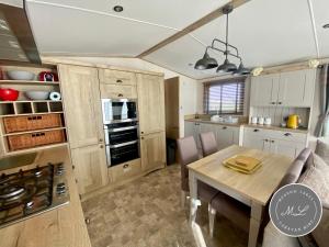 a kitchen and dining room with a table and chairs at Waterside mini lodge - pet friendly, WiFi, direct beach access & club on site - Meadow Lakes Caravan & Lodge Hire in Ingoldmells