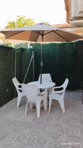 ein weißer Tisch, zwei Stühle und ein Regenschirm in der Unterkunft Apartamento agradable 2 in Madrid