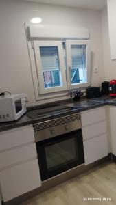 eine Küche mit einem Herd und einer Mikrowelle in der Unterkunft Apartamento agradable 2 in Madrid