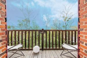 een veranda met 2 stoelen en een bakstenen muur bij L'Écrin de Verdure - Pavillon avec piscine partagée in Thouars