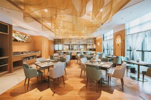 a restaurant with tables and chairs and a large ceiling at SILQ Hotel & Residence, Managed by The Ascott Limited in Bangkok