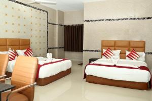 1 Schlafzimmer mit 2 Betten mit roten und weißen Kissen in der Unterkunft Le Royal in Chennai