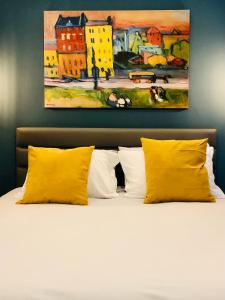a bed with yellow pillows and a painting on the wall at G&G city center luxury studio in Thessaloniki