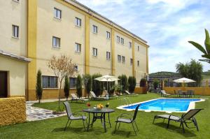 a courtyard with a table and chairs and a pool at Hotel Ciudad de Plasencia in Plasencia