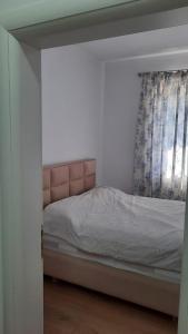 a bed with a pink headboard in a bedroom at City Center Apartment Vjosa River in Memaliaj