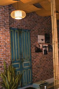 zielone drzwi w ceglanej ścianie ze światłem w obiekcie Nhà Quê Homestay w mieście Nha Trang