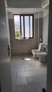 a bathroom with two toilets and a window at City Center Apartment Vjosa River in Memaliaj