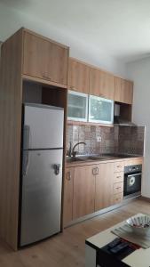 a kitchen with a white refrigerator and wooden cabinets at City Center Apartment Vjosa River in Memaliaj