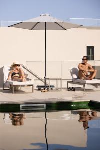 two people sitting on lounge chairs next to the water at Marinha Prime in Cascais