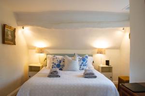 1 dormitorio con cama blanca y almohadas azules en Top Cottage, Oddington, en Adlestrop