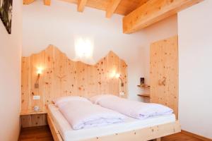 a bed in a room with a wooden wall at Laerchhof in Collalbo