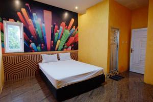 Schlafzimmer mit einem Bett mit Wandgemälde in der Unterkunft Wisma Pelangi Palopo RedPartner in Palopo