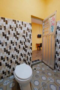 a bathroom with a toilet and a tile wall at Wisma Pelangi Palopo RedPartner in Palopo