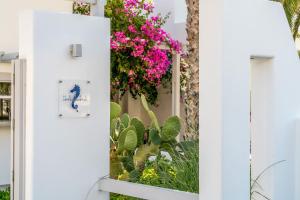 een raam in een wit huis met roze bloemen bij Hippocampus Hotel in Kamari