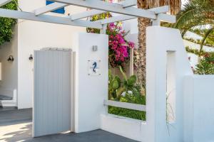 a white fence with a gate and flowers at Hippocampus Hotel in Kamari