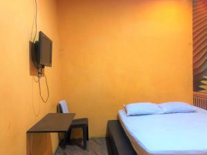 1 dormitorio con 1 cama, TV y escritorio en Wisma Pelangi Palopo RedPartner, en Palopo