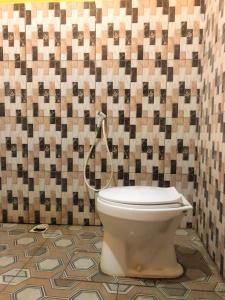 a toilet in a bathroom with a tiled wall at Wisma Pelangi Palopo RedPartner in Palopo