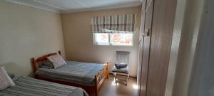 布菲尔斯巴埃Sailaway Beach House的一间有两张床和一扇窗户的小卧室