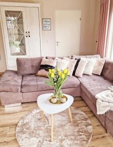 un soggiorno con divano e tavolo con fiori di Nordseeperle Nordholland, mit Sauna, Dirkshorn a Dirkshorn