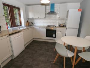 uma cozinha com armários brancos e uma mesa e cadeiras em Cheshire House em Castleton