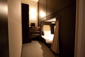HEARTS Capsule Hotel & Spa Nakasu -Male only- في فوكوكا: غرفة صغيرة بها سرير ومكتب