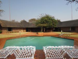 a swimming pool with two white chairs around it at Forest Cabin at Loodswaai between Dinokeng and Cullinan 