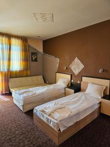 a hotel room with two beds and a window at Къща за гости Виктория in Dobrinishte