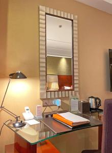 een bureau in een hotelkamer met een lamp en een spiegel bij Merry Hotel Shanghai (Former Rendezvous Merry Hotel Shanghai) in Shanghai
