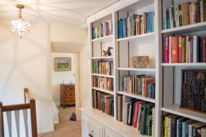 a room with white bookshelves filled with books at Top Cottage, Oddington in Adlestrop